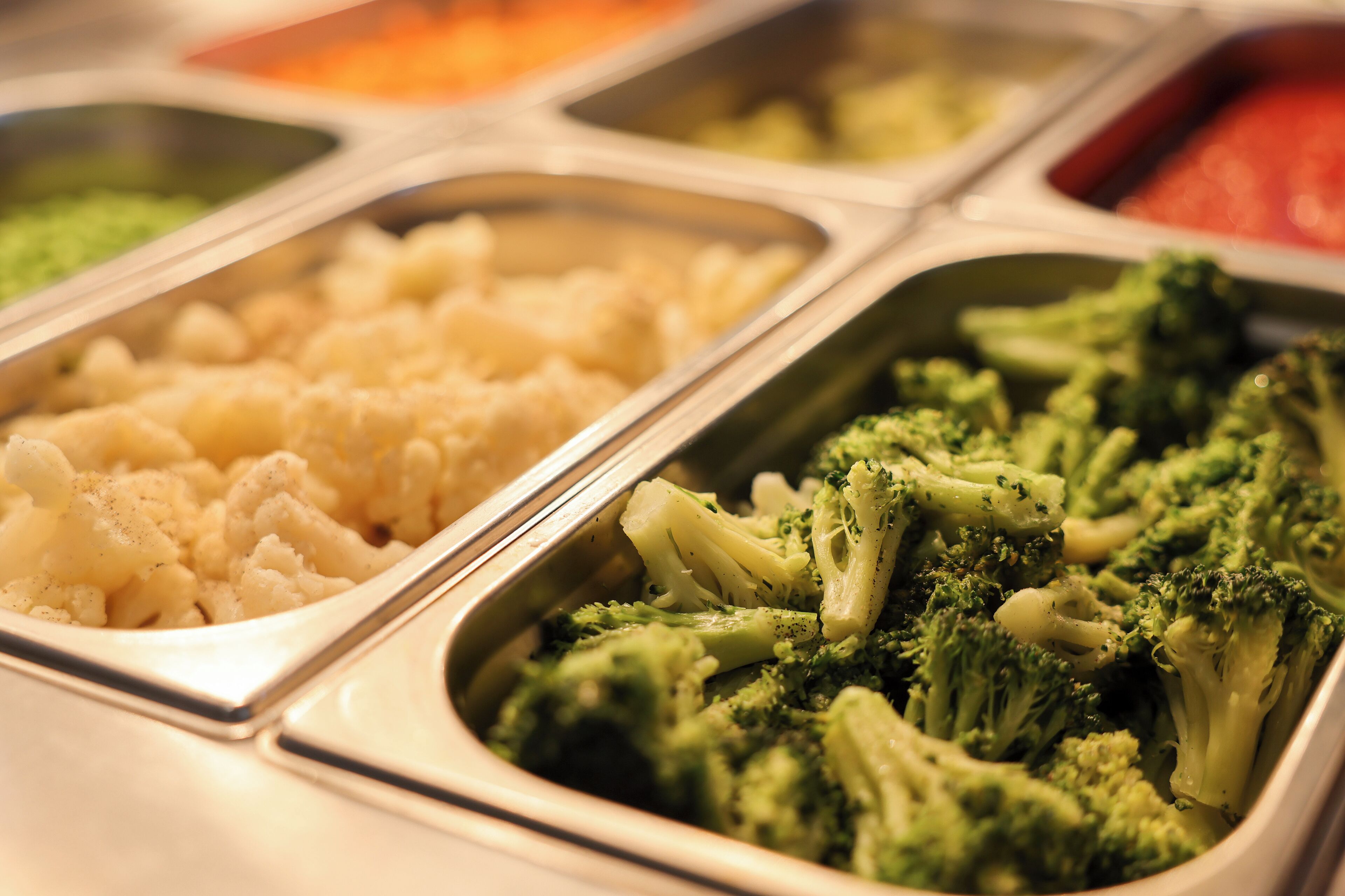 A buffet with various food options including cauliflower and broccoli.
