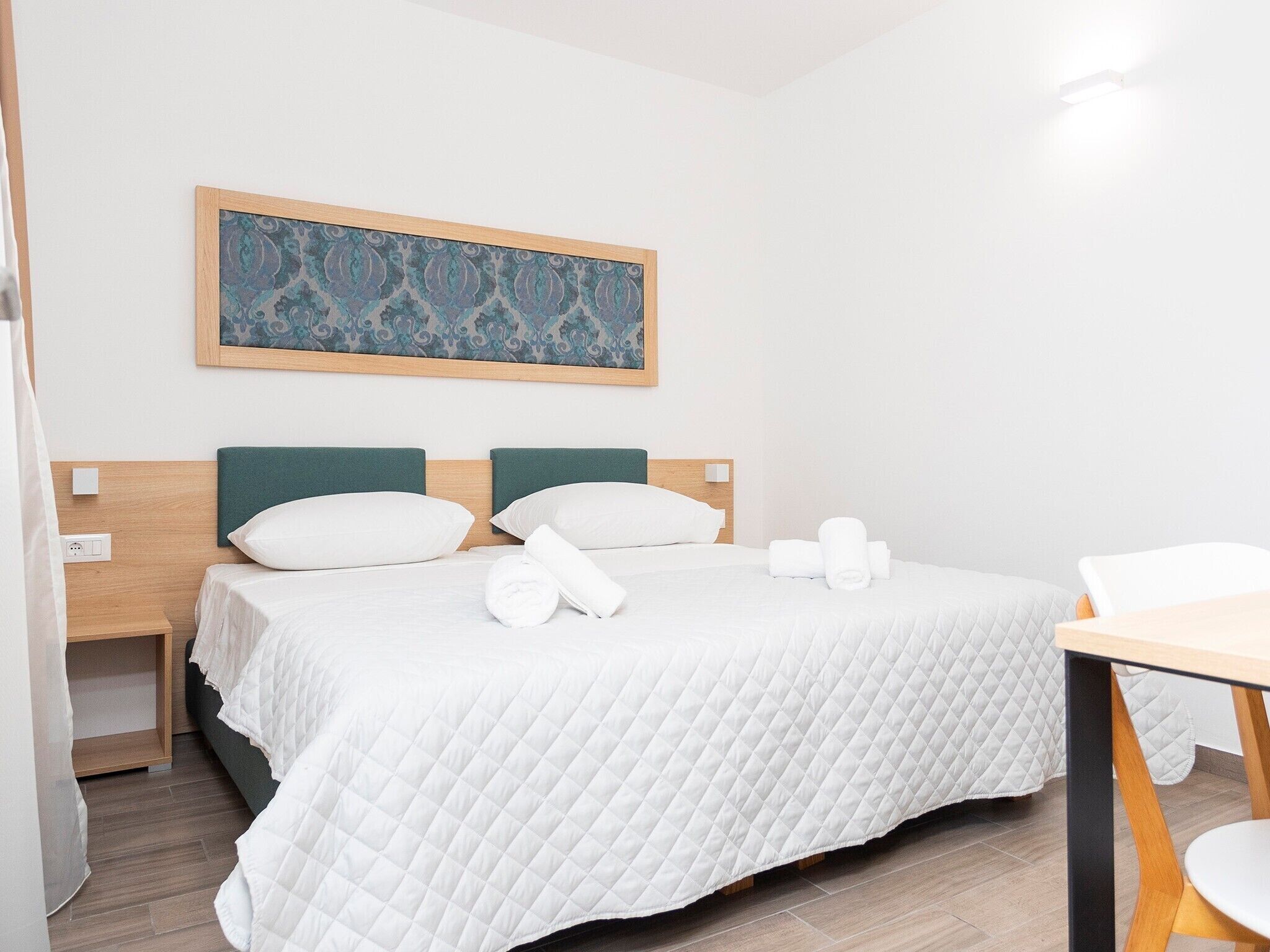 Una habitación de hotel con una cama, un cuadro en la pared y una mesita.