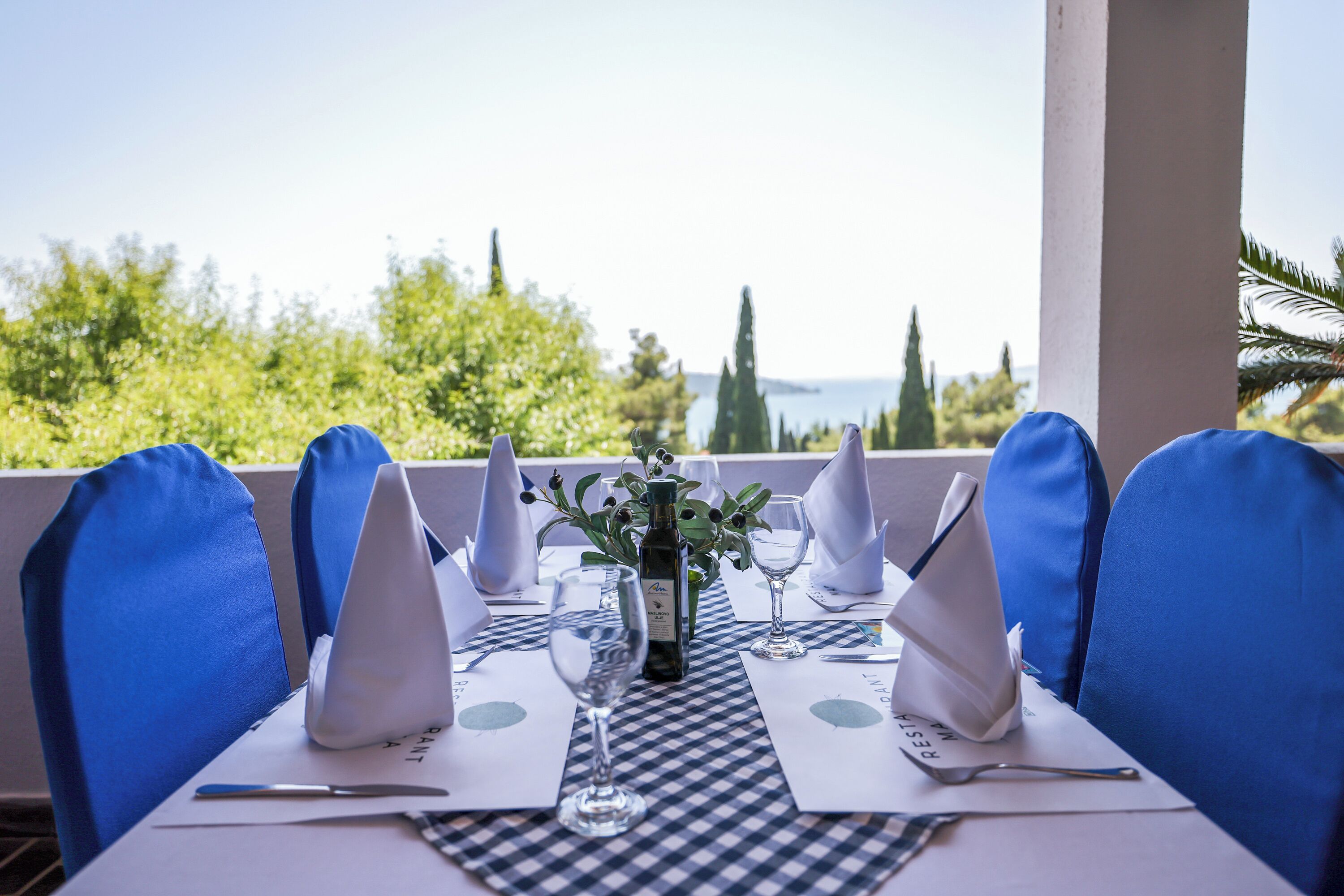 A table set for dining with a view of greenery and a body of water.