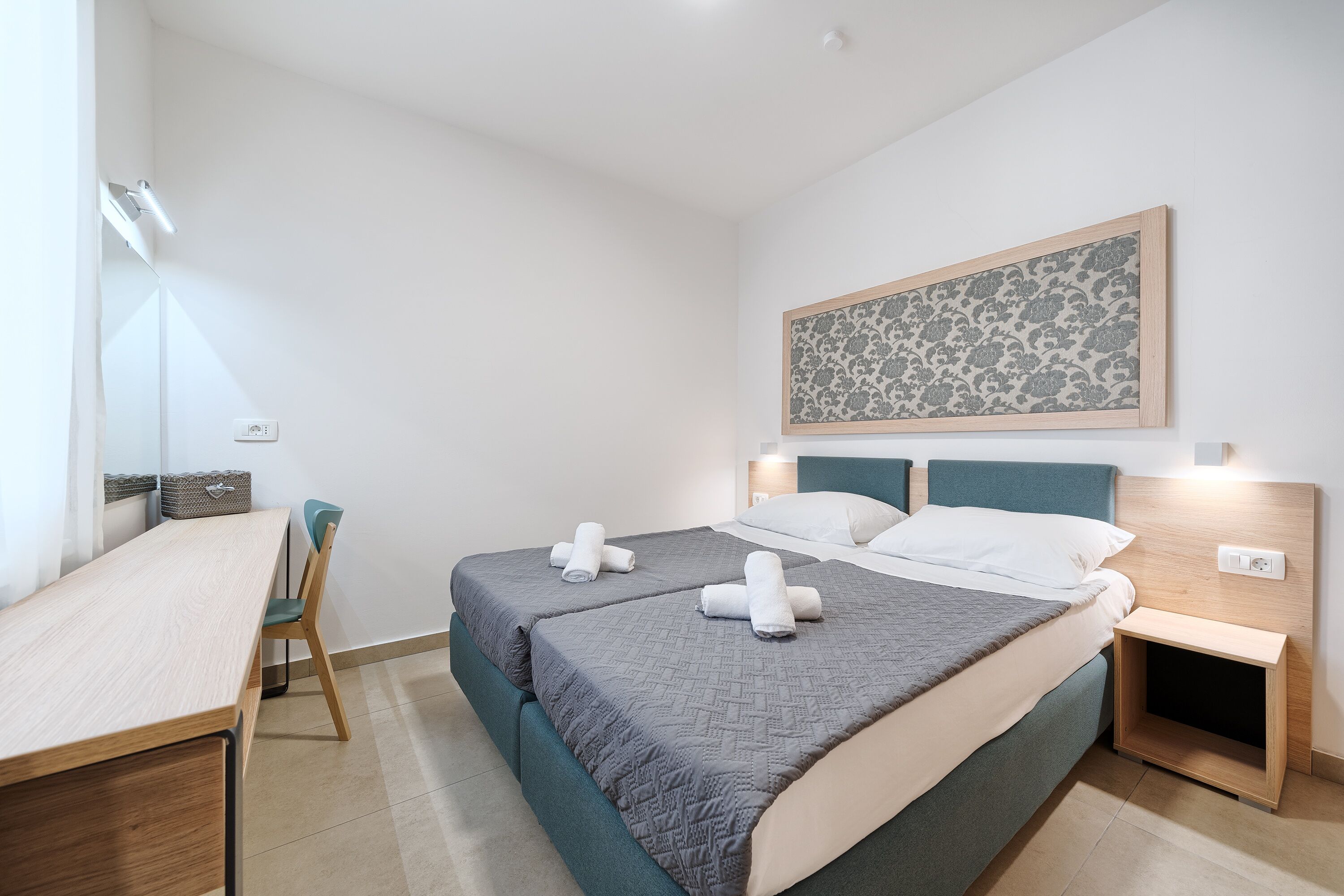 Ein Schlafzimmer mit einem Bett, Nachttischen, einem Schreibtisch und einem Stuhl.