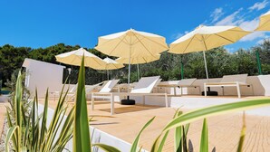 A poolside area with lounge chairs and umbrellas, surrounded by greenery. - Apartments Medena (Seget)