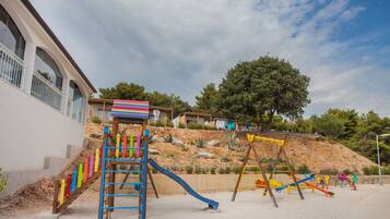 Children can play on the slide, climbing structure, and swings in this outdoor playground.
