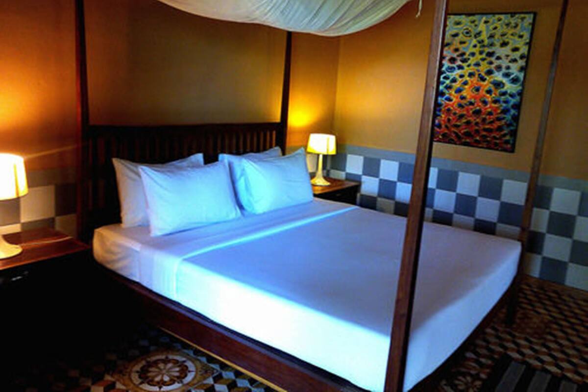 Una habitación de hotel con una cama con dosel, una pared a cuadros y un suelo estampado.