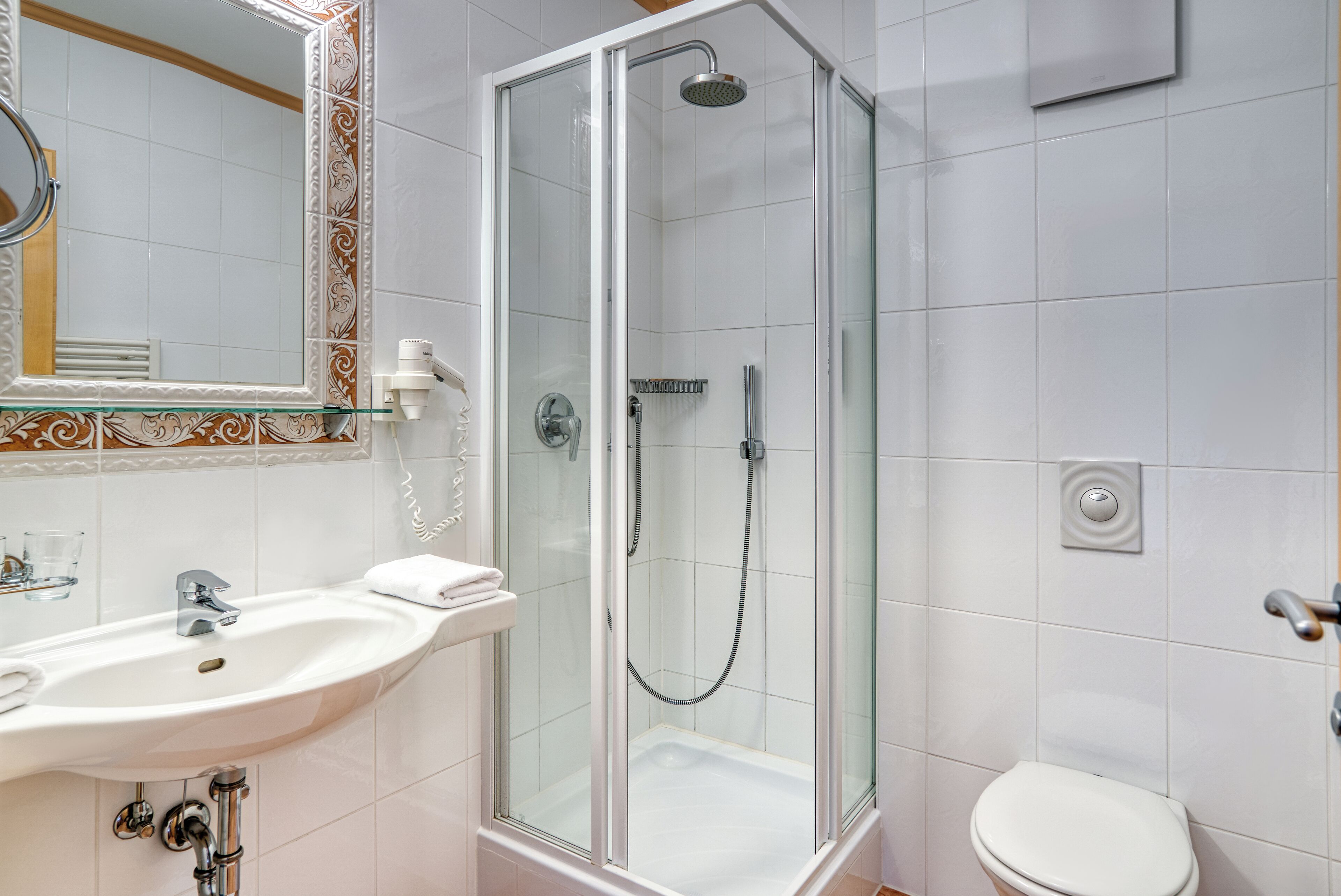 A bathroom with a glass-enclosed shower, a white sink, and a toilet.