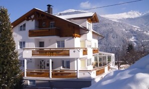 A multi-story chalet with wooden balconies, set against a snowy mountain backdrop. - Hotel Venetblick (Jerzens)