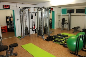 A gym with exercise equipment, green mats, and a digital clock. - Landhotel Wolf (Leutasch)
