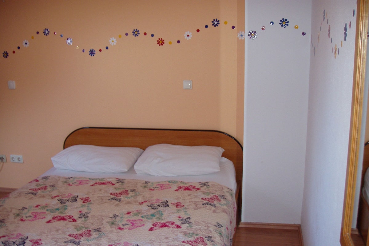 Une chambre à coucher avec un lit, une couvre-lit à motifs floraux et des décorations murales.