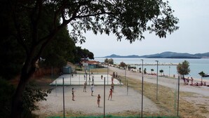 En volleybollplan med spelare, ett nät och en strand i bakgrunden.