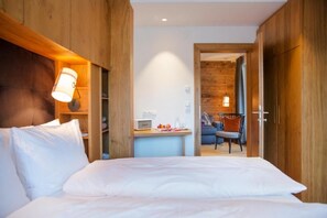 Una habitación de hotel con cama, lámpara de noche, armario de madera y un escritorio con silla.