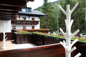 A wooden deck with white sculptures, a building with balconies, and a forested mountain in the background. - Valluga (Sankt Anton am Arlberg)