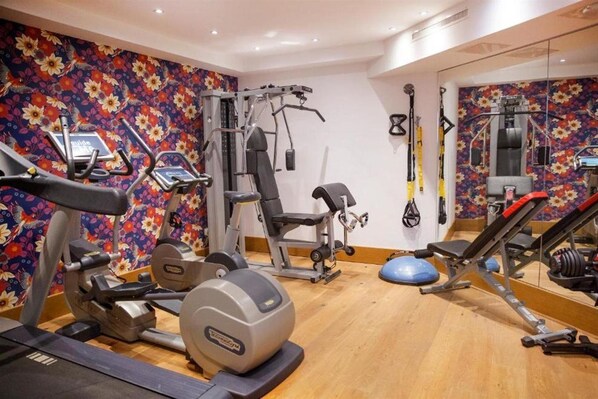 Un gimnasio con máquinas de cardio, equipo de levantamiento de pesas y un muro de espejos.