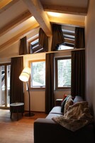 Una habitación acogedora con un sofá, una lámpara y un ventanal con cortinas.