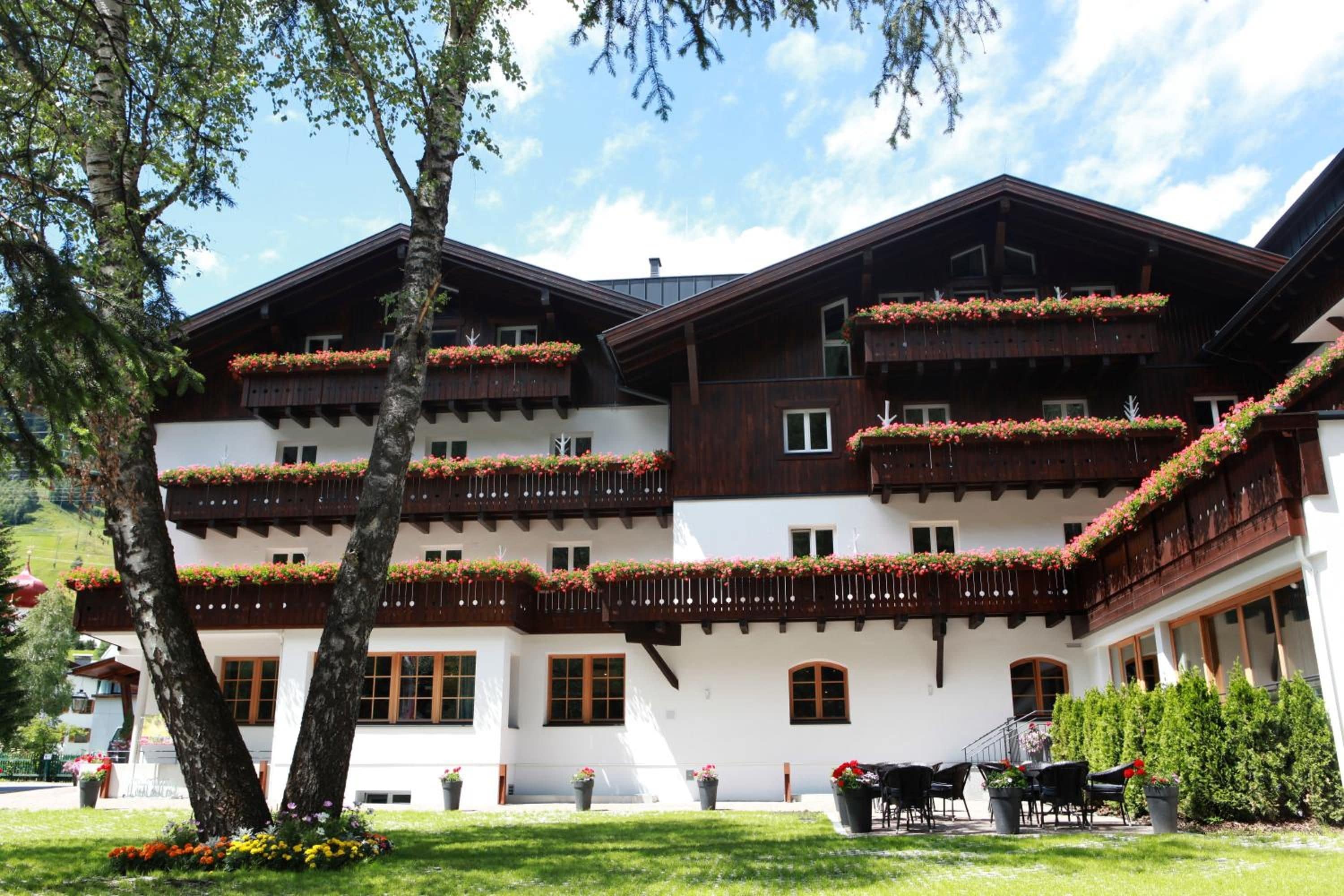 A multi-story building with balconies adorned with flowers, a well-maintained lawn, and outdoor seating.