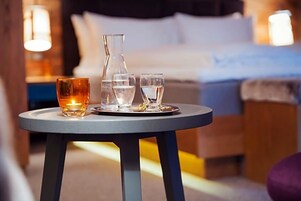 A round table with a candle, a glass of water, and a glass of wine in a hotel room.