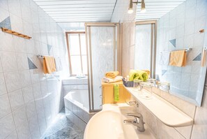 A bathroom with a bathtub, a sink, and a shower. - Hotel Gasthof Gribelehof (Lienz)