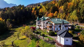 A large, multi-story building with a green roof, surrounded by a well-maintained garden and a forested hillside. - Hotel Gasthof Gribelehof (Lienz)