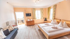 A hotel room with a bed, a sofa, a TV, and a wooden dresser. - Hotel Gasthof Gribelehof (Lienz)