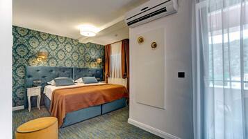 Habitació d'hotel amb un llit, una tauleta de nit, un aparell d'aire condicionat, una finestra amb cortines i un paper pintat amb un disseny.