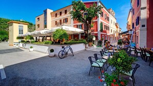 Un espace café en plein air avec des tables et des chaises, un vélo et un bâtiment à la façade rouge.