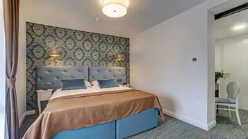Hotelkamer met een groot bed, twee nachtkastjes, een hoofdeinde en behang met een patroon.