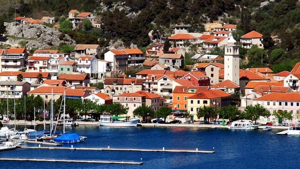 Une ville côtière avec des bâtiments le long du front de mer, un port de plaisance rempli de bateaux et une tour imposante.