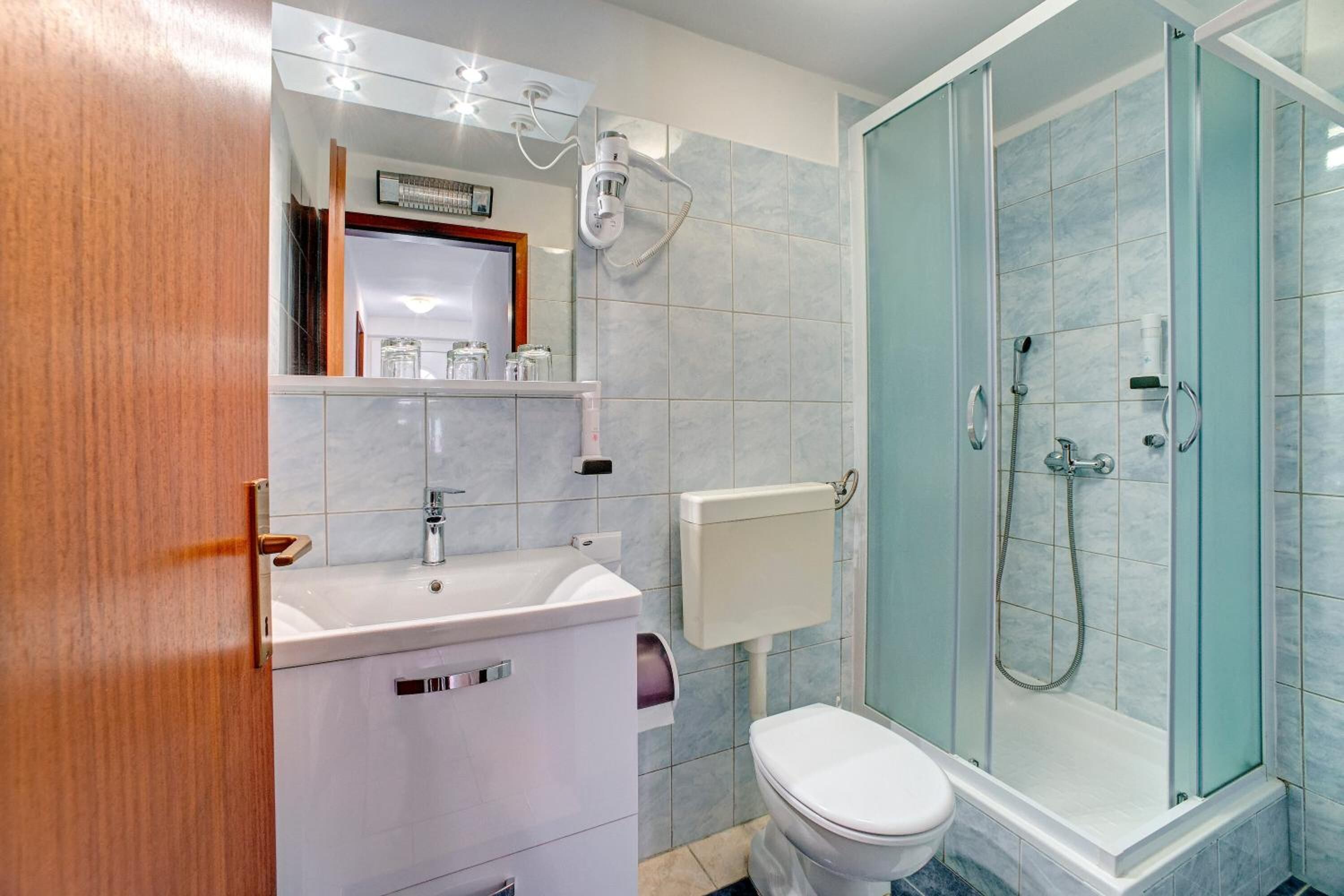 Een badkamer met een wit wastafelmeubel, spiegel, toilet en een douchecabine.