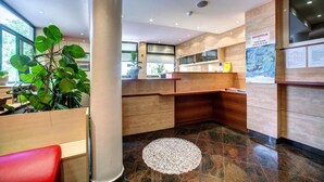 Un espace d’accueil avec des meubles en bois, une plante en pot et un sol carrelé.