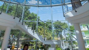 A modern interior with a glass dome ceiling, a reception desk, and a staircase leading to upper levels. - Hotel Villa Radin (Vodice)