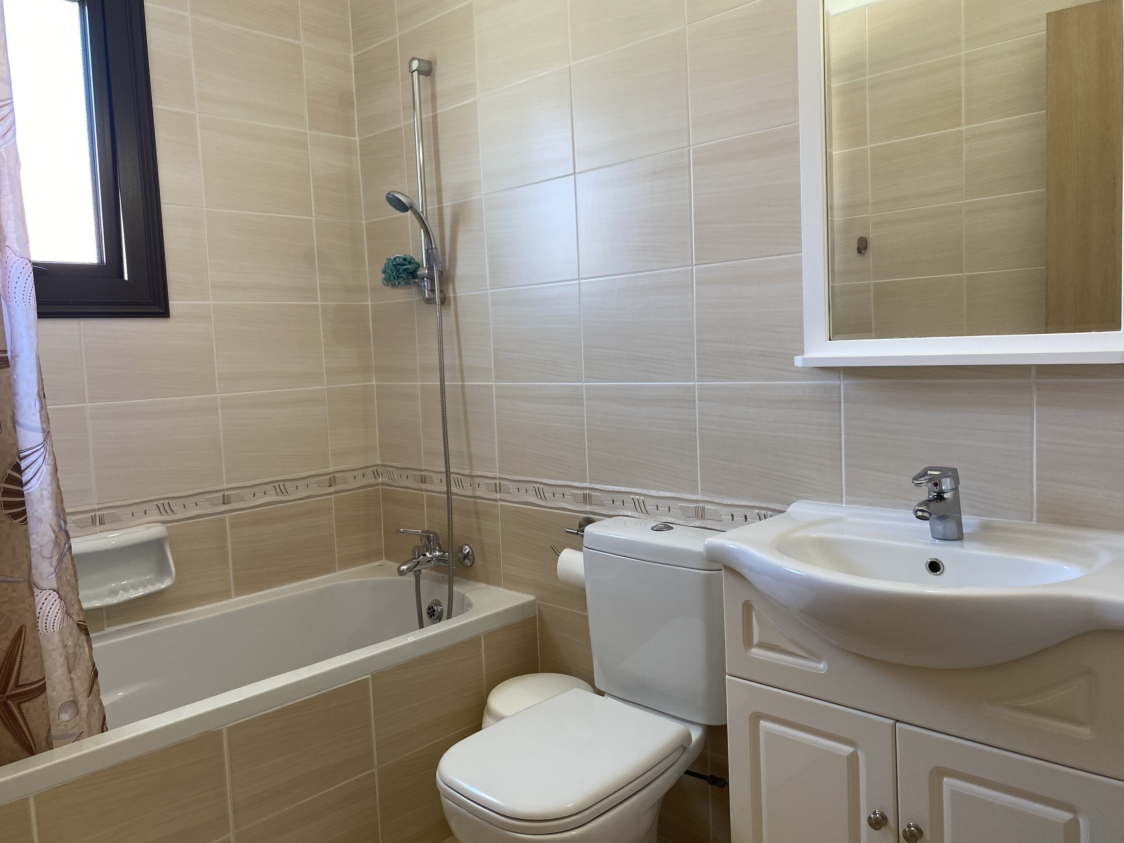 Un baño con bañera, inodoro, lavamanos y espejo.