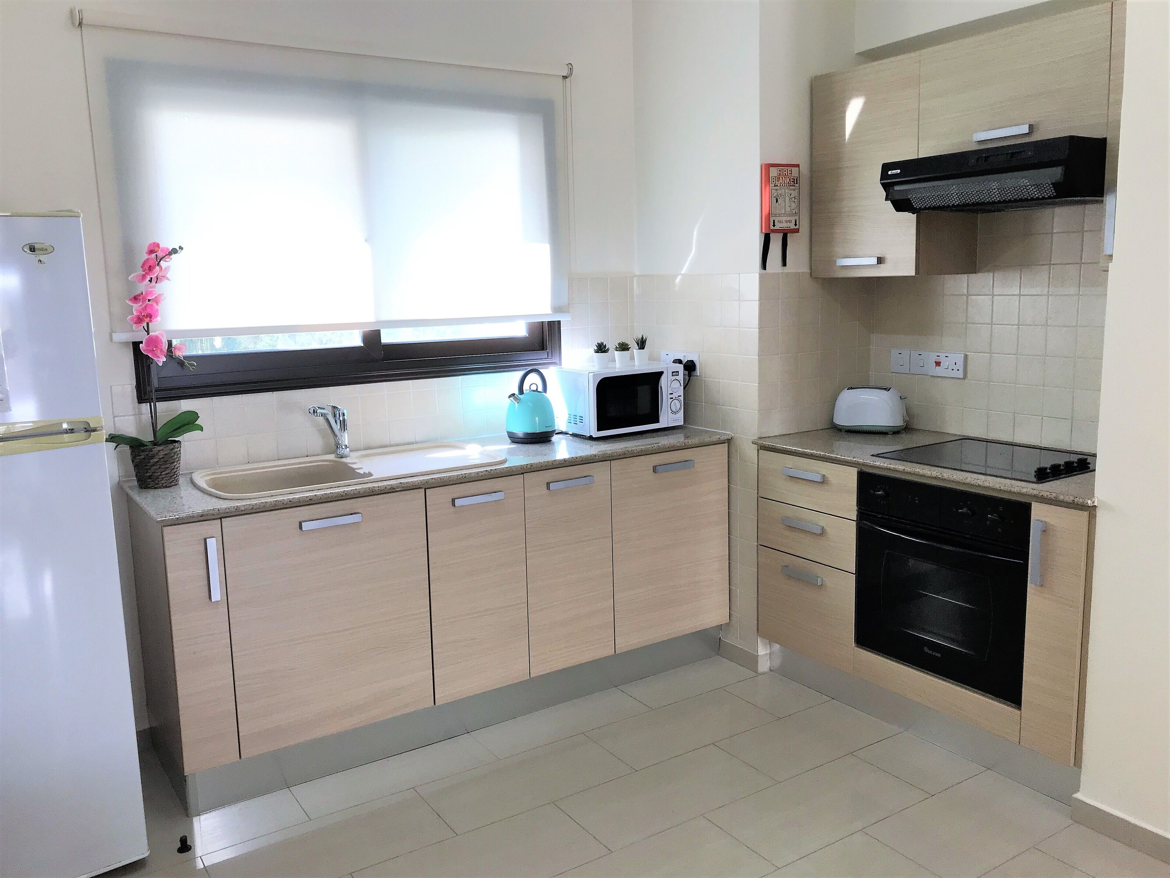 A modern kitchen with a sink, stove, microwave, and toaster.