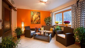 Una sala de estar acogedora con muebles de mimbre, un cuadro grande en la pared y plantas en macetas.