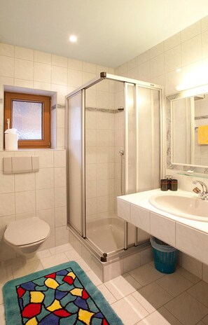 A bathroom with a shower enclosure, a toilet, a sink, and a window. - Top Tirol Appartement (Laengenfeld)