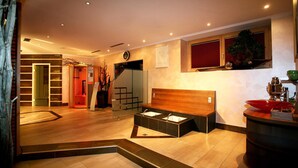 Un moderno vestíbulo de hotel con un banco de madera, un mostrador de recepción, una escalera y un ventanal con marco rojo.