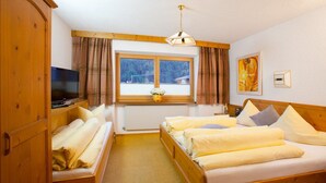Una habitación de hotel con cama, televisión, ventana con cortinas y un cuadro en la pared.