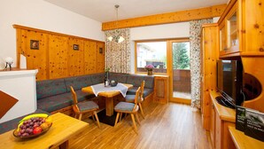 Una habitación acogedora de estilo cabaña, con paredes de madera, una mesa de comedor con sillas, un sofá y un televisor.