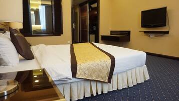 A hotel room with a bed, a bedside table, a lamp, a television, and a mirror.