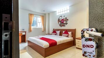 Une chambre d’hôtel comprenant un lit, un bureau, une fenêtre avec des rideaux et un élément décoratif mural.