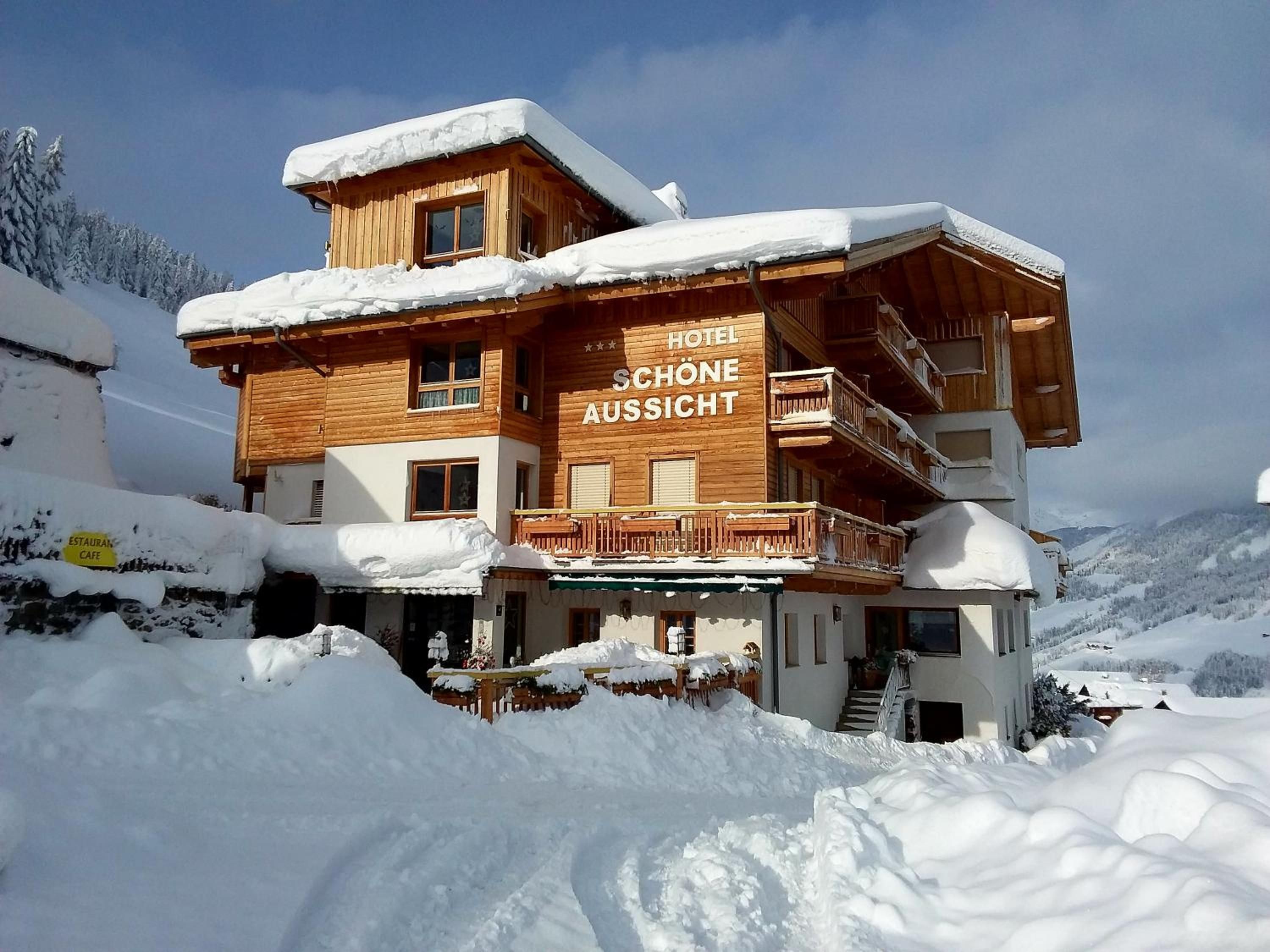 A wooden chalet hotel with a balcony and a sign reading 'Hotel Schöne Aussicht.'