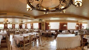 Un comedor amplio con varias mesas y sillas, un espacio central para sentarse y un techo decorativo.