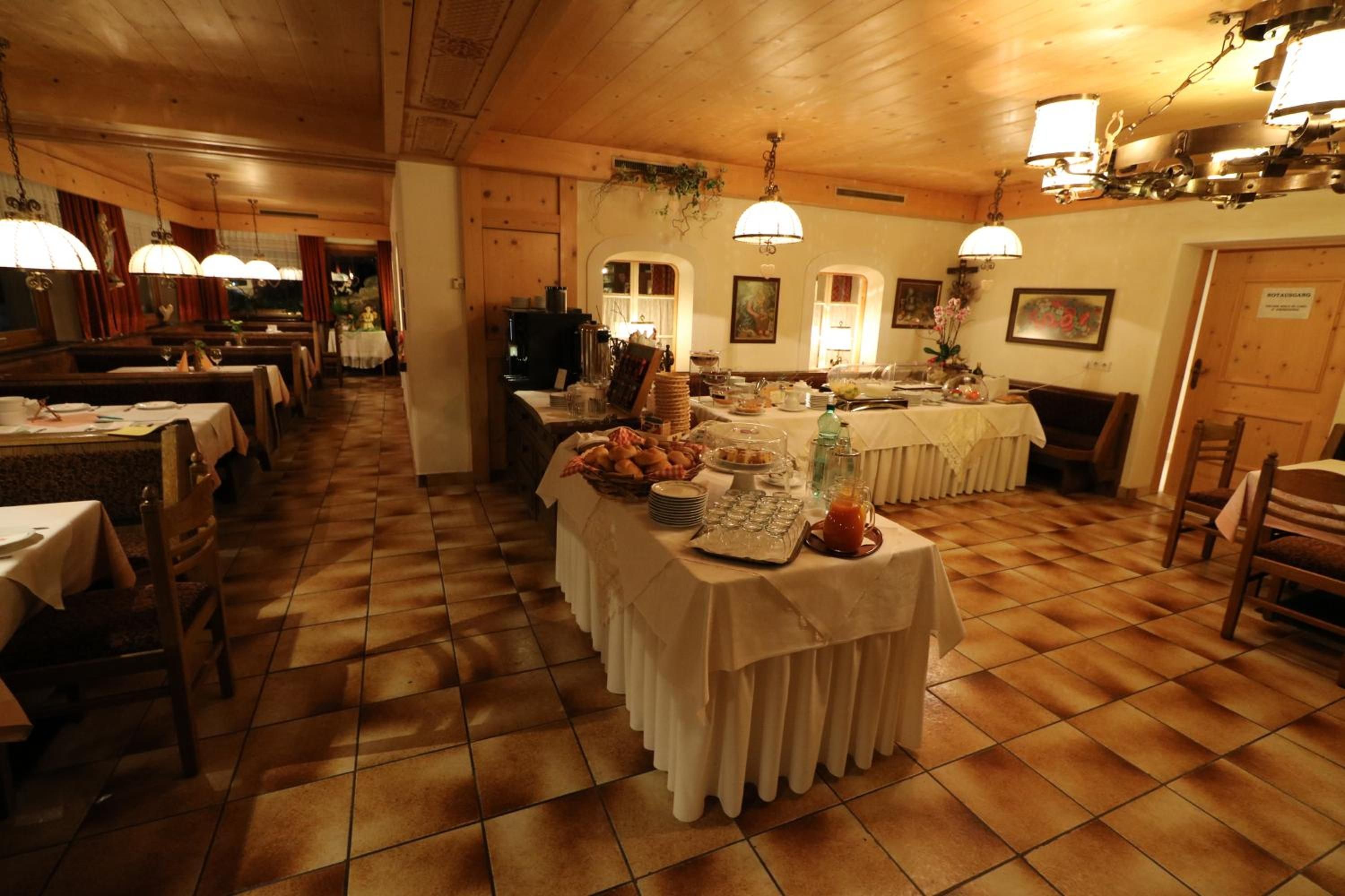 Ein Restaurant mit mehreren Tischen, einem Buffet und einem Holzboden.