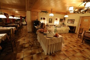 A restaurant with multiple tables, a buffet setup, and a wooden floor.