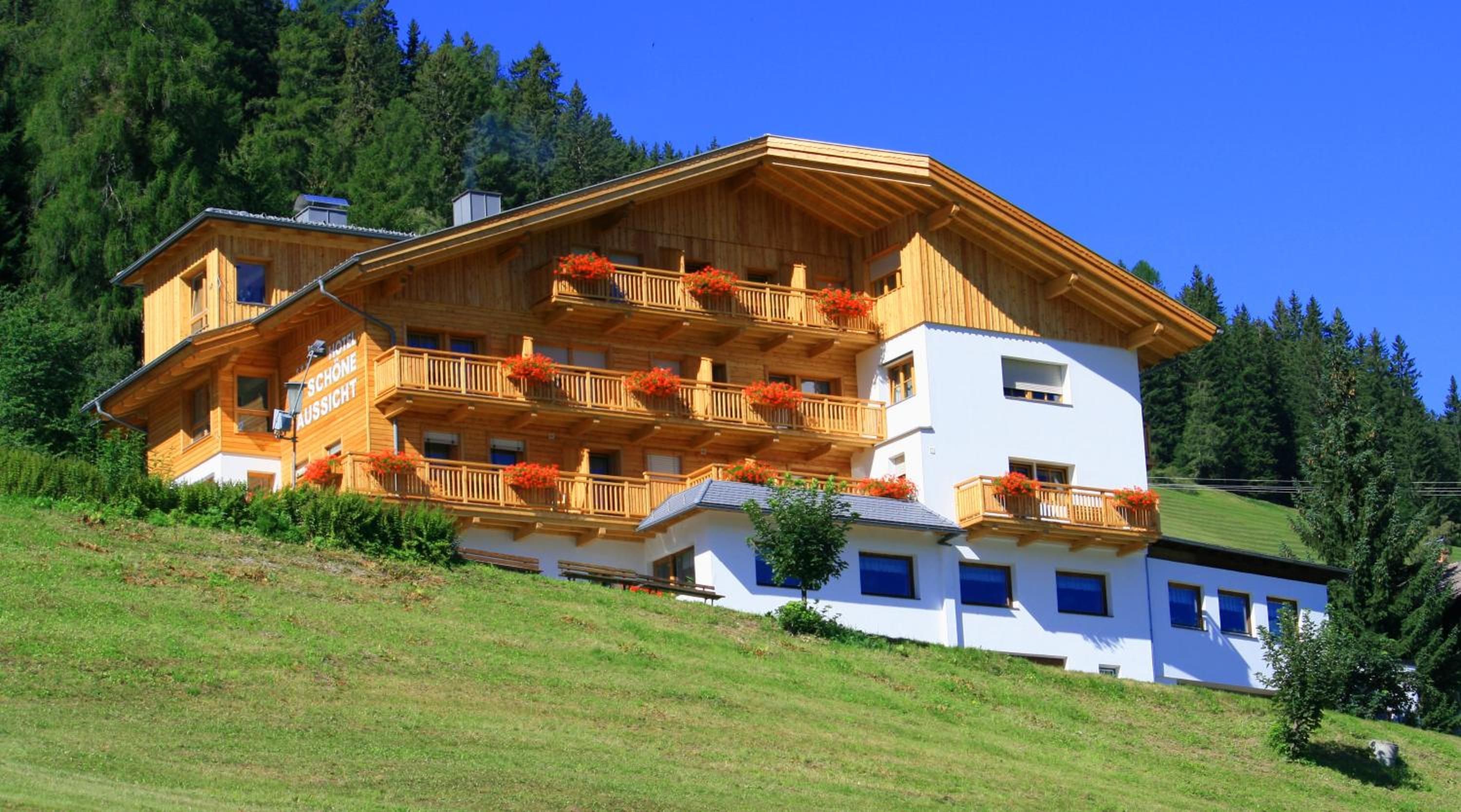 Un bâtiment en bois à plusieurs étages, doté de balcons, vraisemblablement un hôtel, situé sur une colline, avec un ciel dégagé.