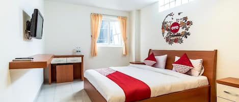 A bedroom with a bed, a desk, a chair, a television, and a window with curtains.
