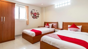Habitación de hotel con dos camas, un armario, una ventana con cortinas y un adorno en la pared.