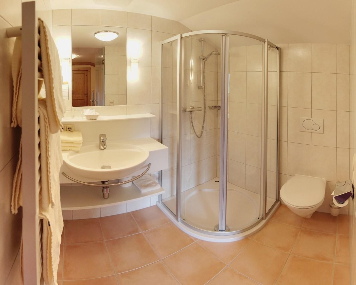 Un baño moderno con ducha vidriada, lavamanos e inodoro.