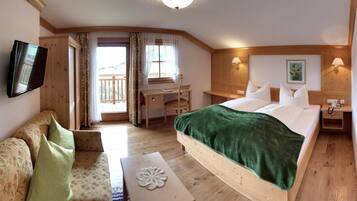 Une chambre d’hôtel comprenant un lit, un bureau, une chaise, une télévision et un balcon.