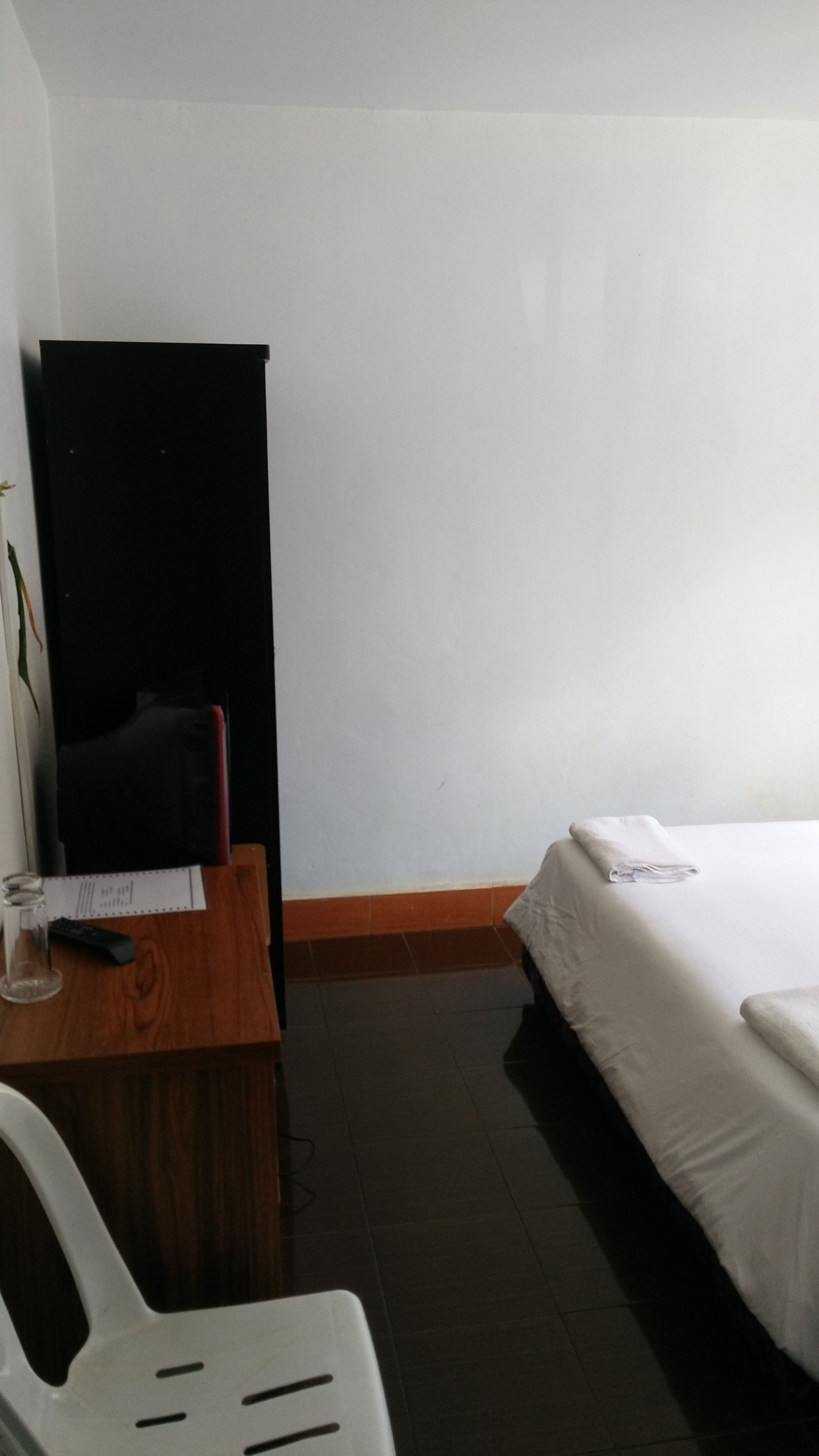 A small, simple room with a bed, a desk, and a chair.