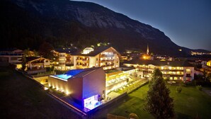 Un hotel amplio y bien iluminado con varias construcciones, piscina y montañas al fondo.