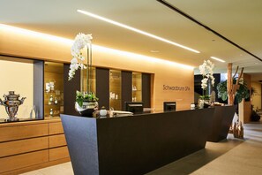 A reception desk with a modern design, a wooden counter, and a sign that reads "Schwarzwald SPA". - Hotel Schwarzbrunn Superior (Stans)