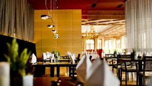 Un restaurante con varias mesas, luces colgantes y una lámpara de araña grande.